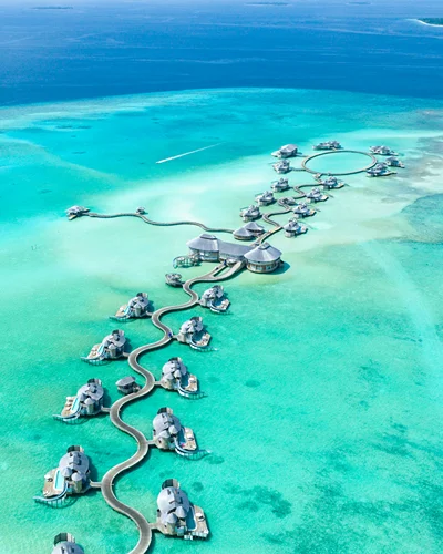 Overwater villas curving across a pale turquoise lagoon