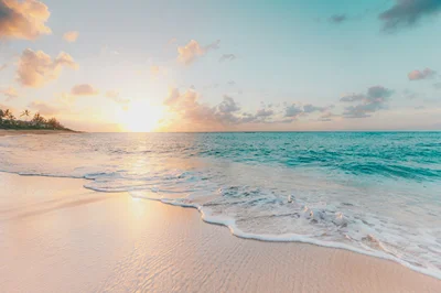 A wide empty beach with turquoise water and white sand
