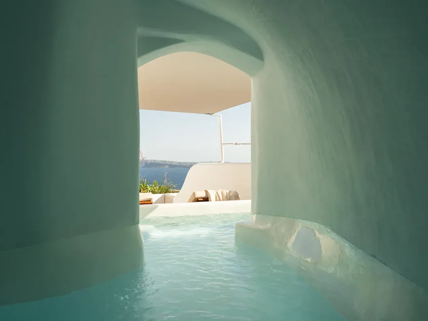 A whitewashed terrace and plunge pool cut into the cliff above the caldera
