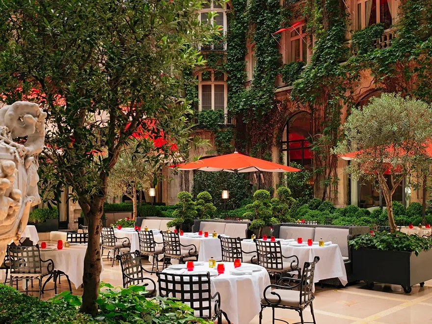An ivy-covered courtyard with red awnings on Avenue Montaigne