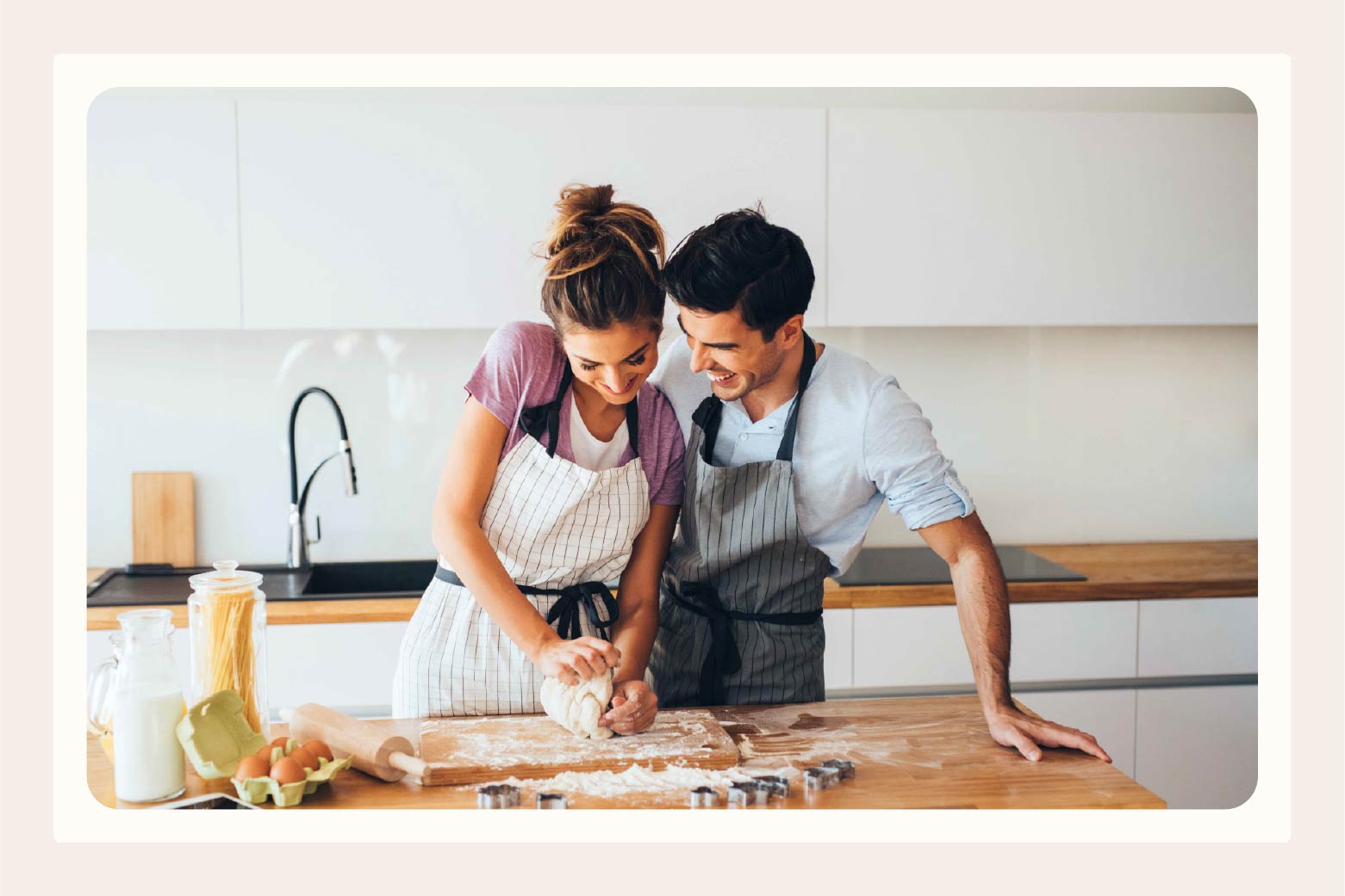 Man and woman standing close together while she kneads cookie dough on kitchen counter