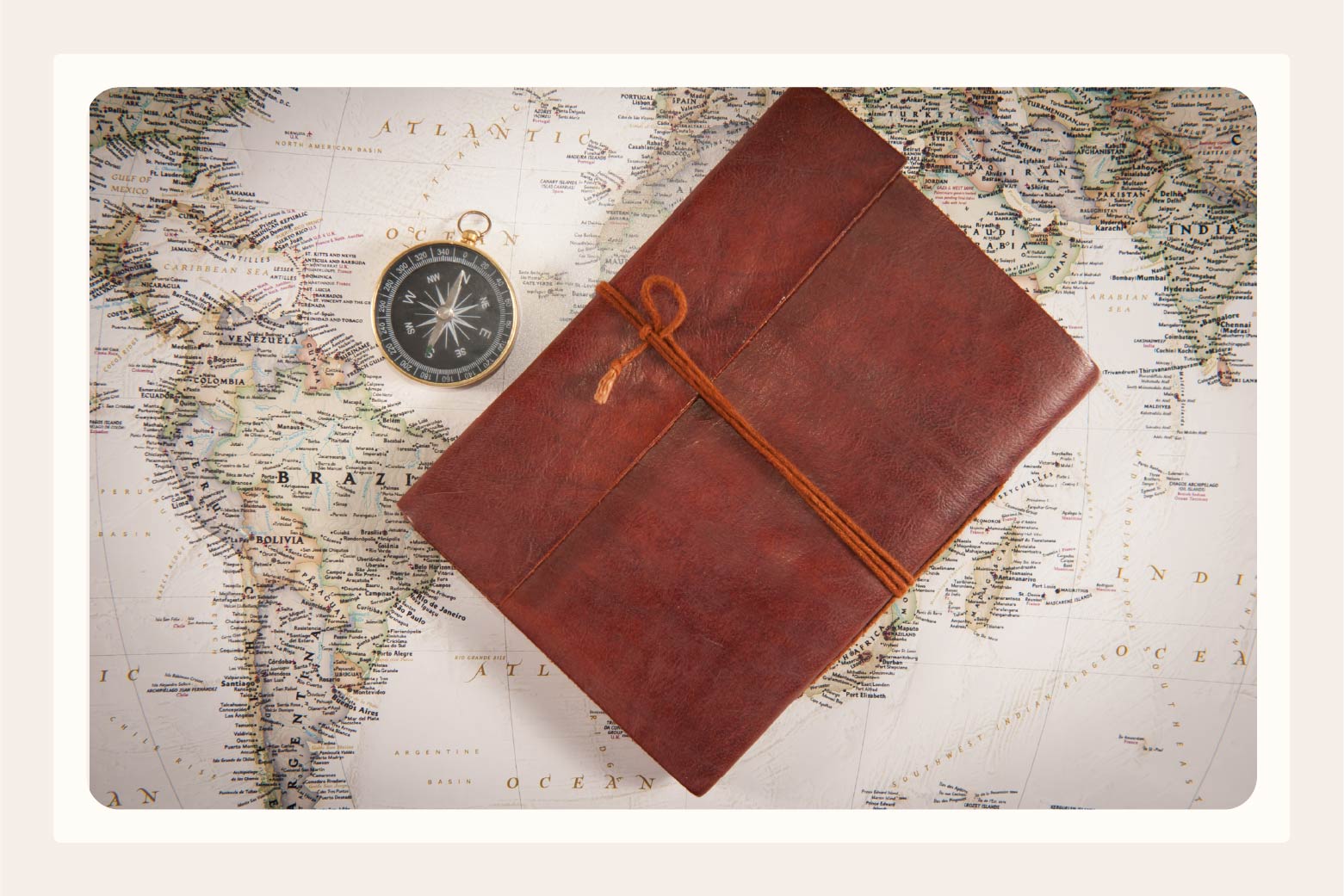 leather-bound journal and compass laying on a world map