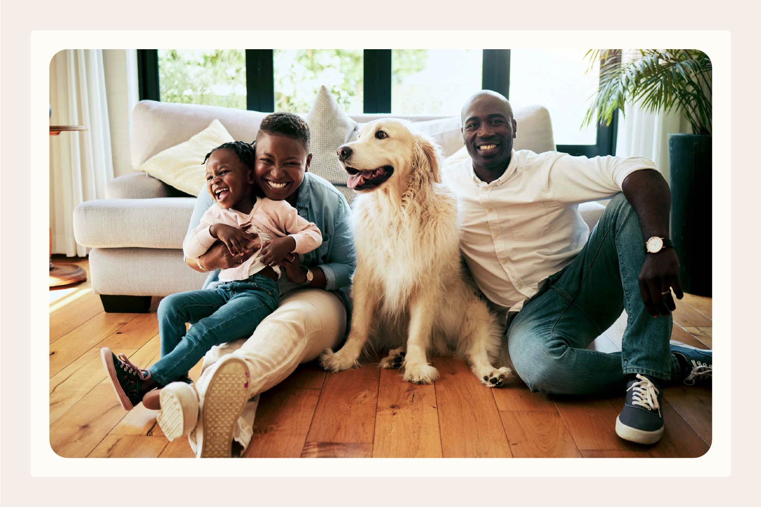 Family of man woman and young child pose with their dog while all sitting on floor