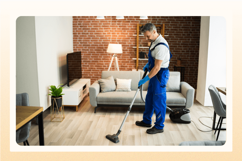 man in overalls and gloves vacuuming living room