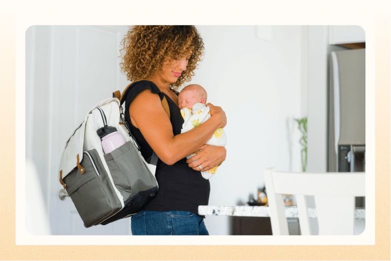 woman with diaper bag over her shoulder holding sleeping newborn wrapped in blanket