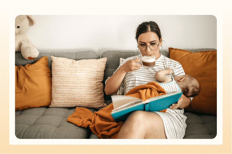 woman sitting on sofa holding a sleeping baby and a book while sipping latte