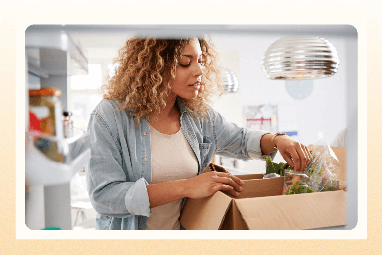 Woman in kitchen looking through box of green vegetables