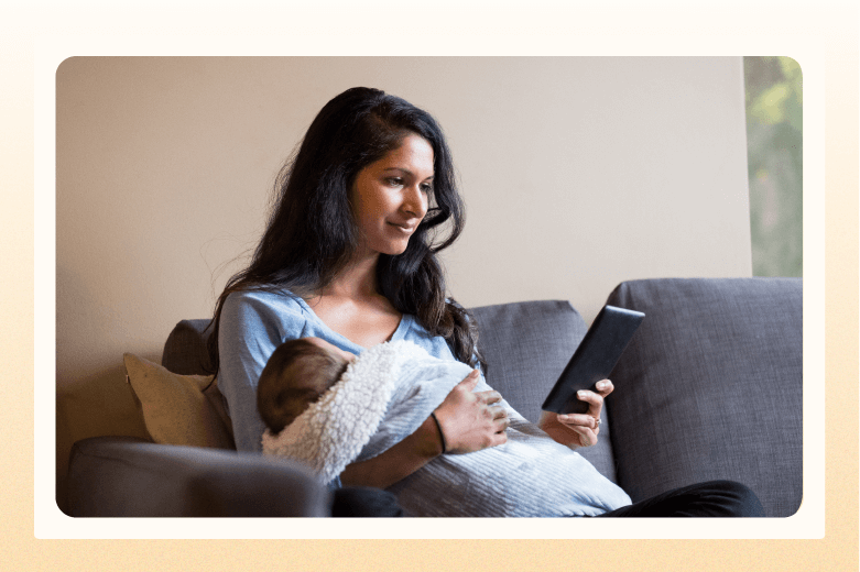 woman holding sleeping baby while reading an e-reader