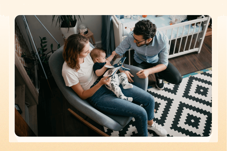 woman sitting in rocking chair in nursery while reading to baby with husband kneeling next to chair