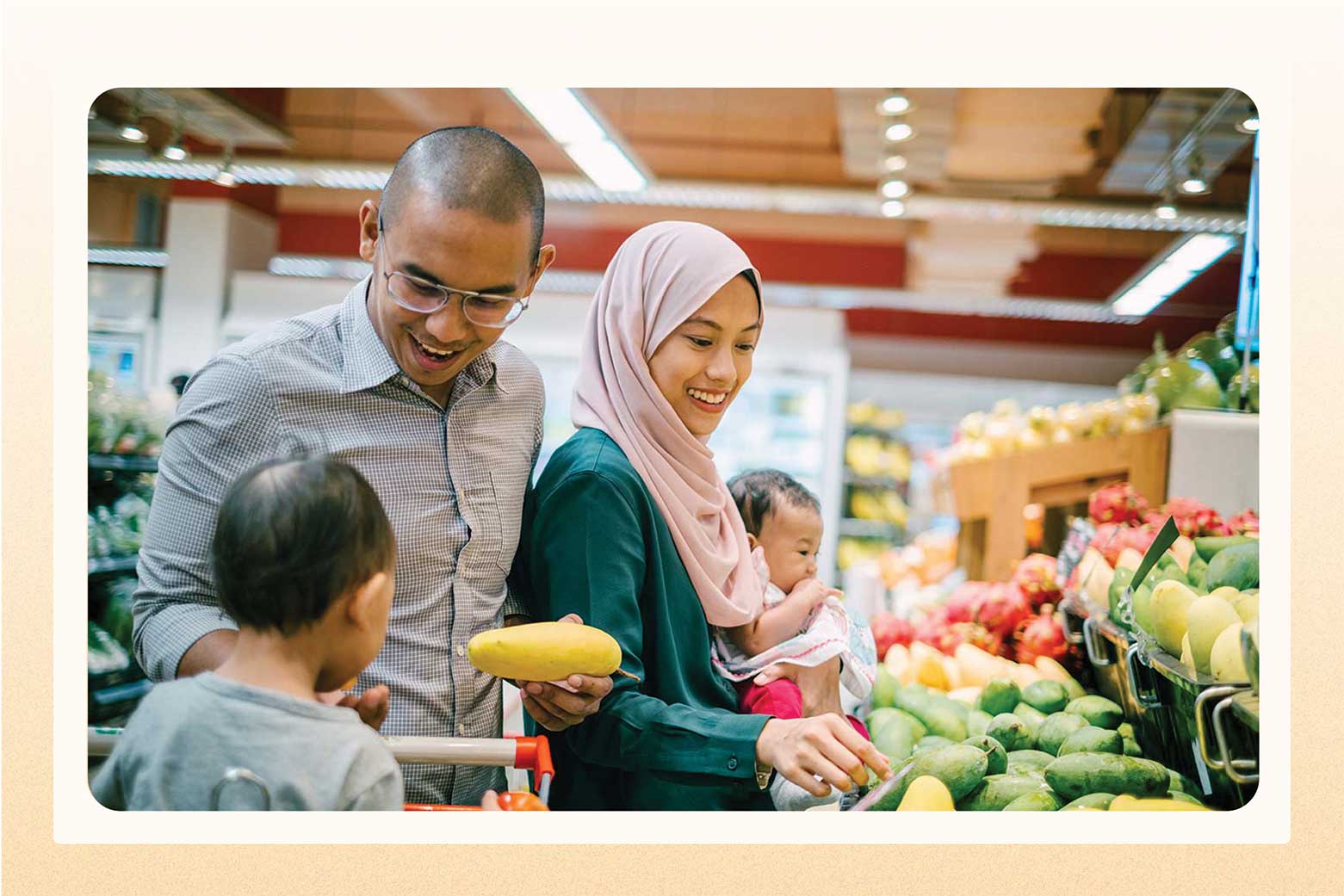 Smiling woman in head scarf with man and two children while grocery shopping in the produce section