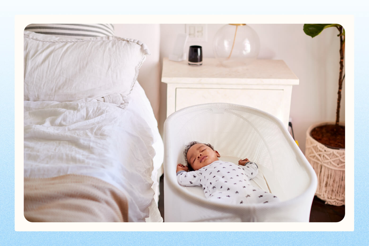 Sleeping baby lays in bassinet positioned next to parents' empty bed