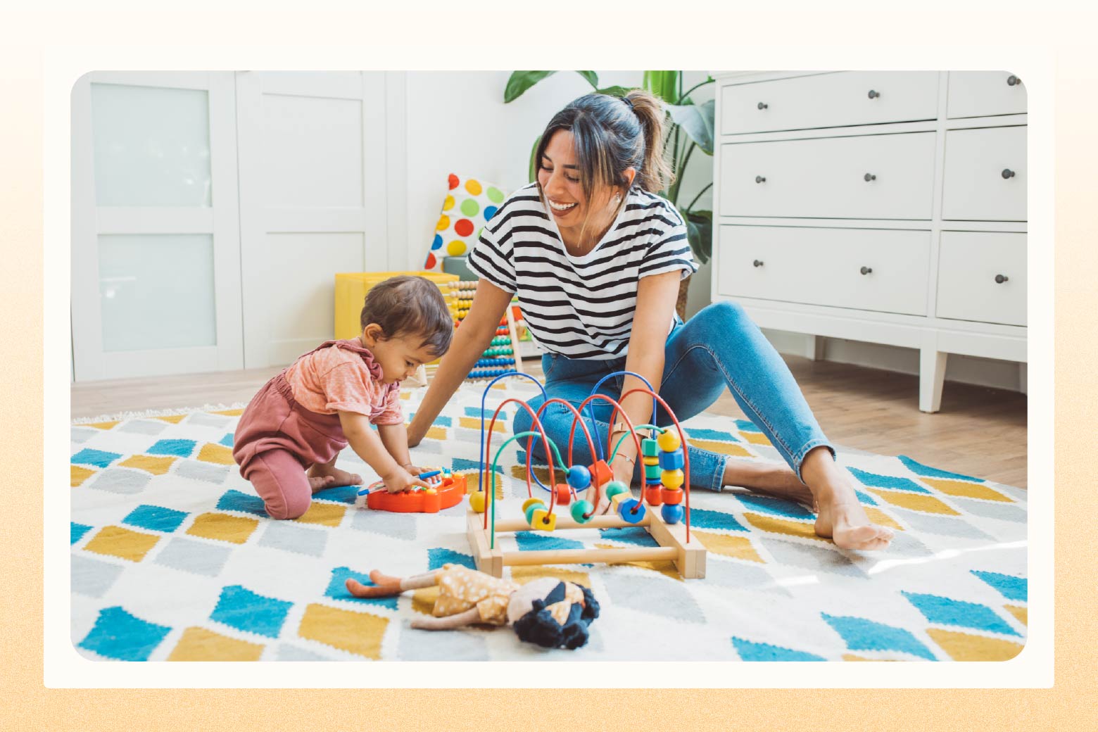 Woman and baby play with toys while sitting on the floor