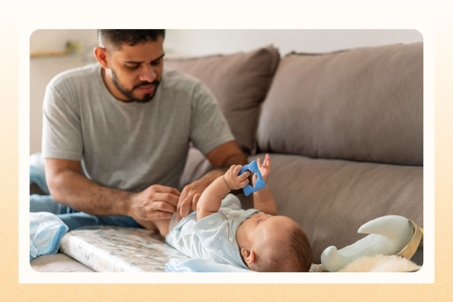 Dad changing baby's diaper on a changing pad laid on a sofa