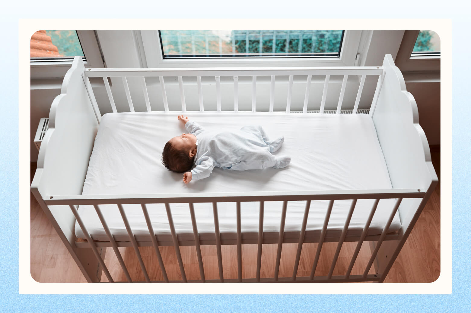 Overhead view of baby lying in a plain white standard crib