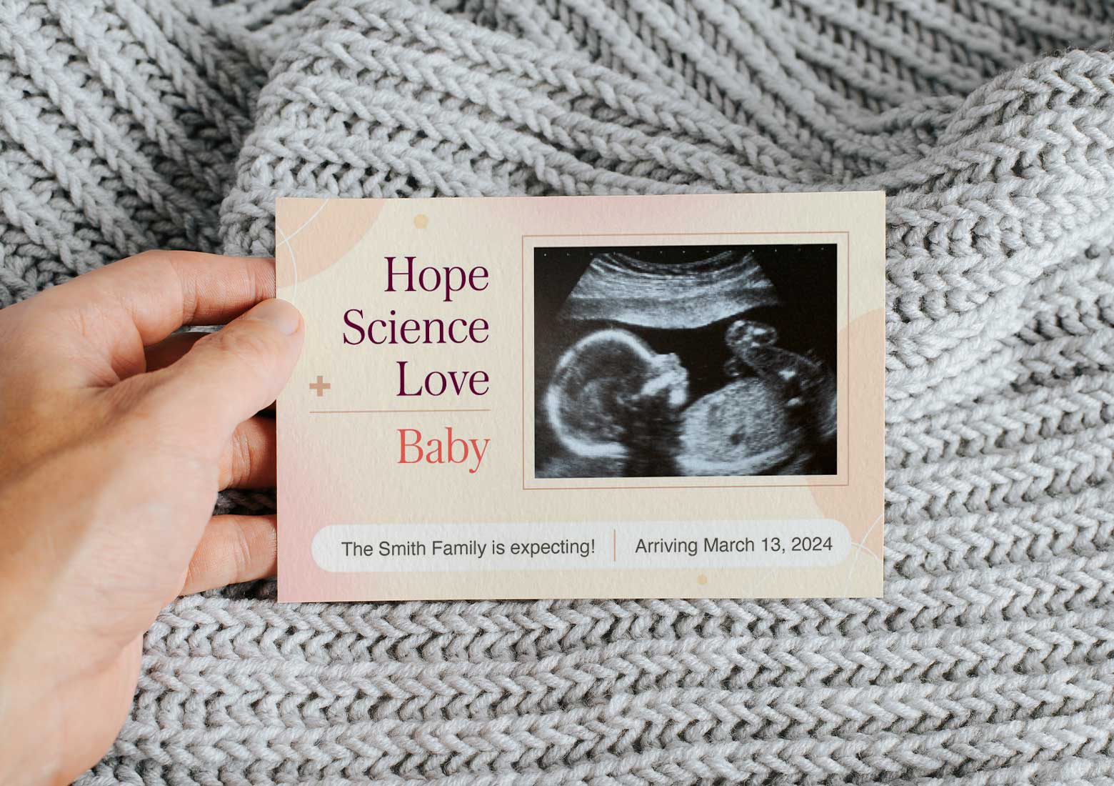 Close up of a hand holding an IVF pregnancy announcement that says Hope + Science + Love = Baby 