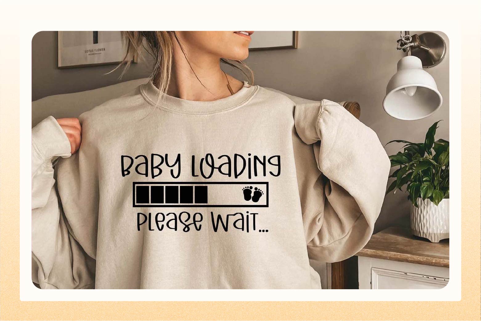 Close up of woman wearing a beige sweatshirt that says "Baby loading, please wait"  