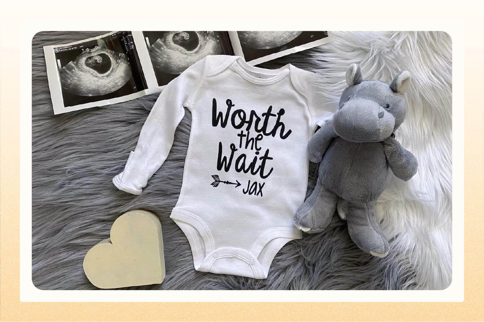 White long sleeved onesie that says "Worth the wait, Jax" laid on grey furry rug next to a sonogram and stuffed animal