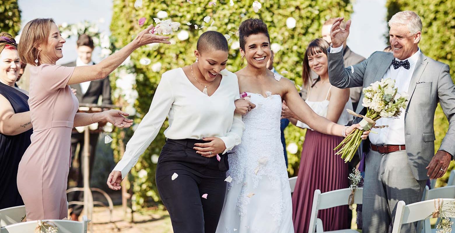 A couple leaving their wedding venue with their guests showering them with confetti.