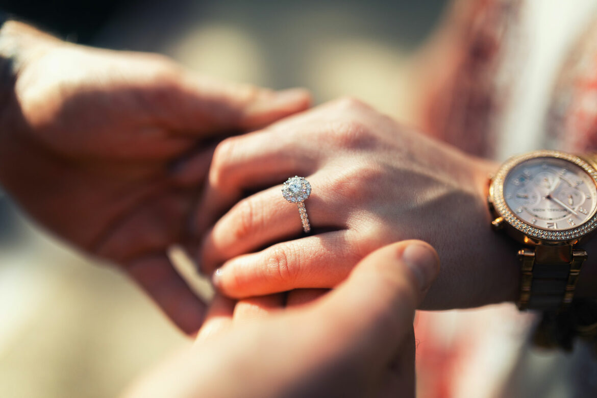 A close-up of an engagement ring on an outstretched hand