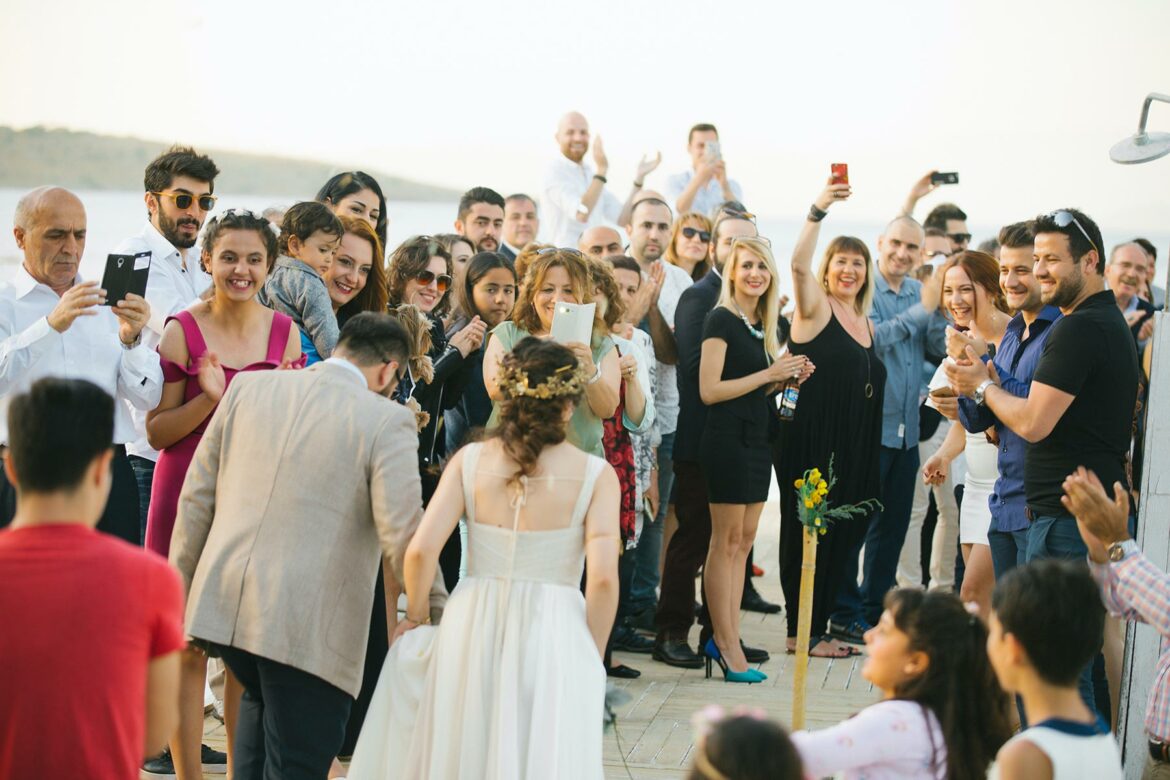 A group of wedding guests cheering for a bride and groom