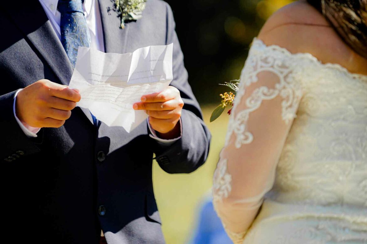 A man in a suit holding his wedding vows as a woman in a dress looks on