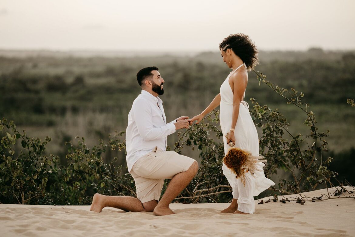 A man on one knee in a beach proposal