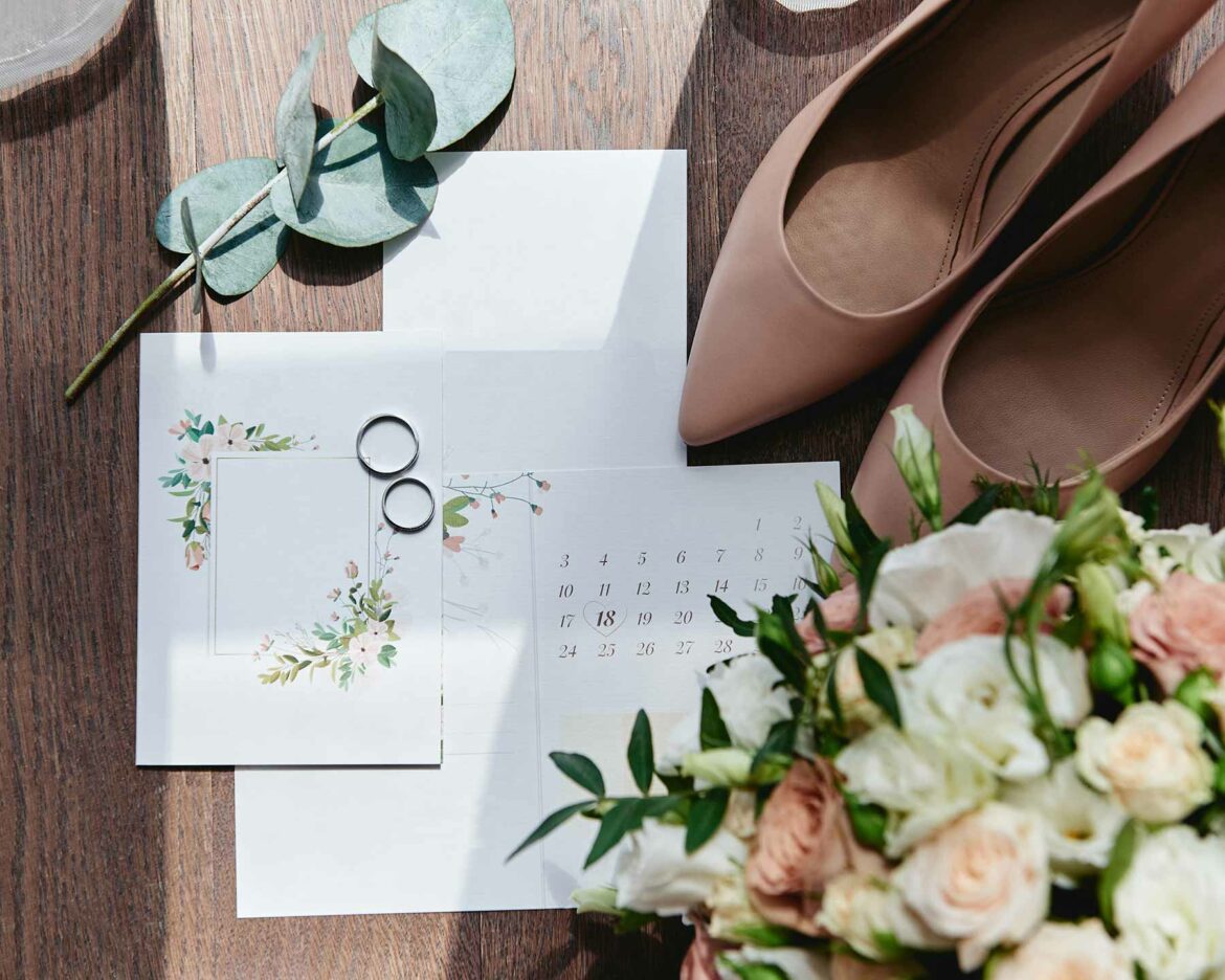 Save the date surrounded by flowers, rings and high heels