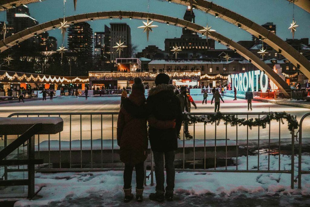 a couple watching an ice skating rink at night