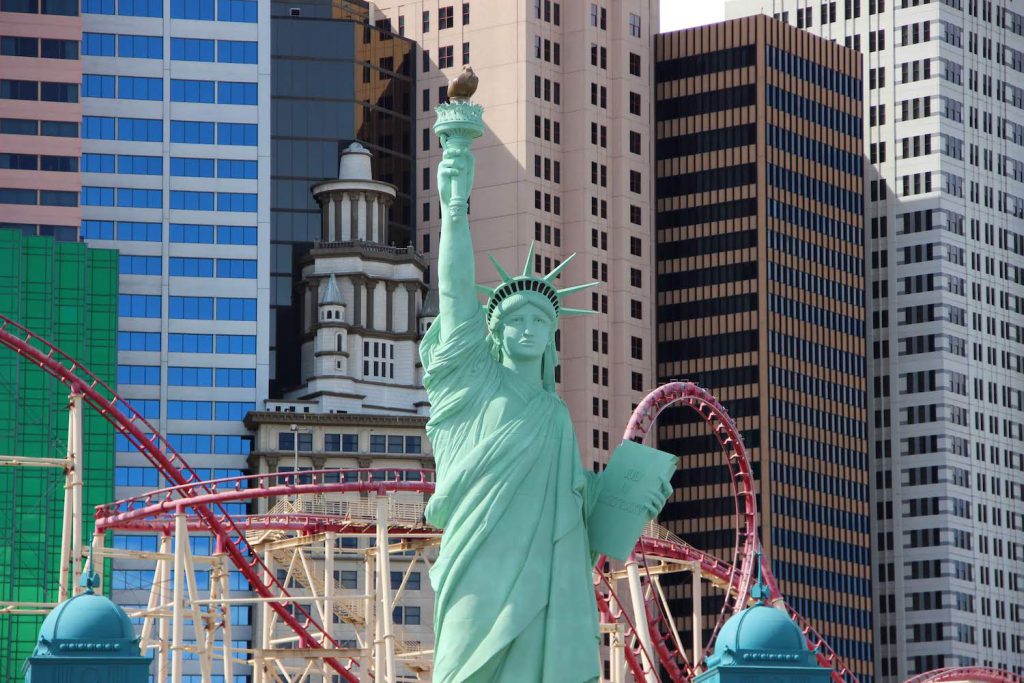 a replica of the statue of liberty in front of the big apple coaster at the new york new york hotel in las vegas