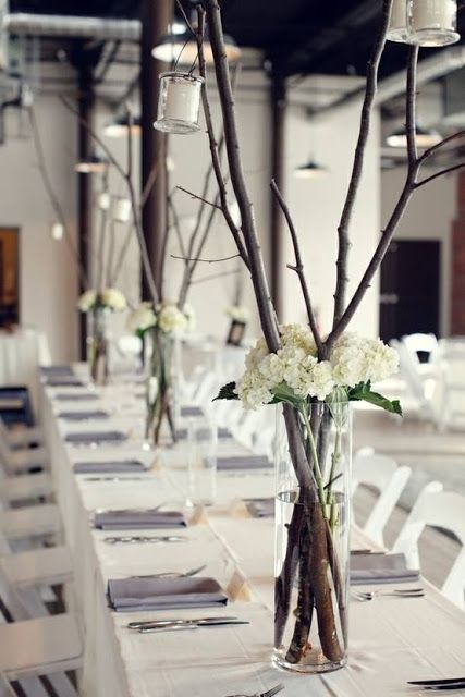 branches and flowers in clear vase centerpieces arranged on a wedding reception table