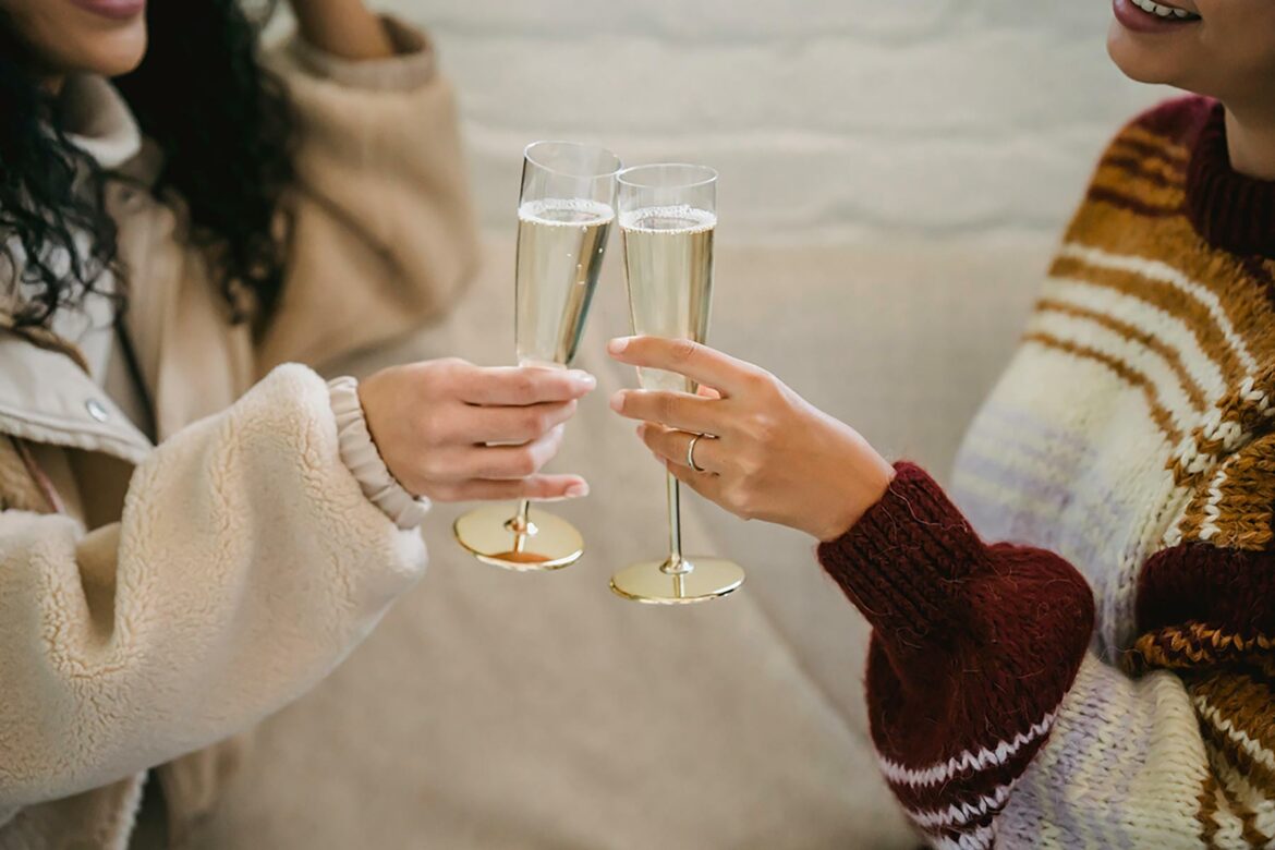Two women clinking champagne glasses at an engagement party