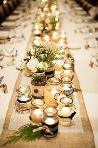 mason jars filled with candles lined up as a centerpiece at a wedding reception table