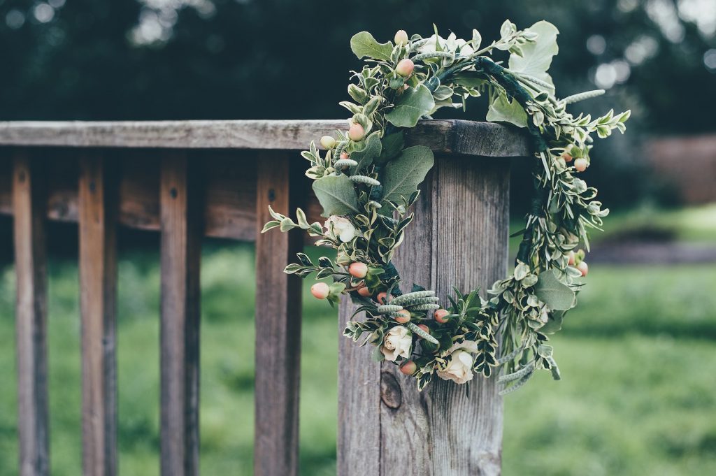 faux flower crown with greenery hanging off wooden post