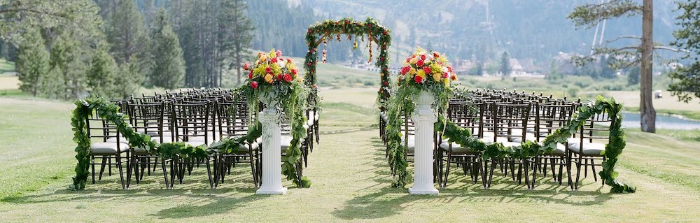 chairs, an arch, and floral displays set up for a wedding on the golf course at the resort at squaw creek