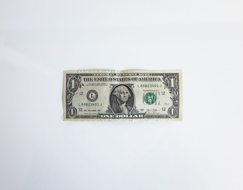 a single dollar pill lying flat on white background