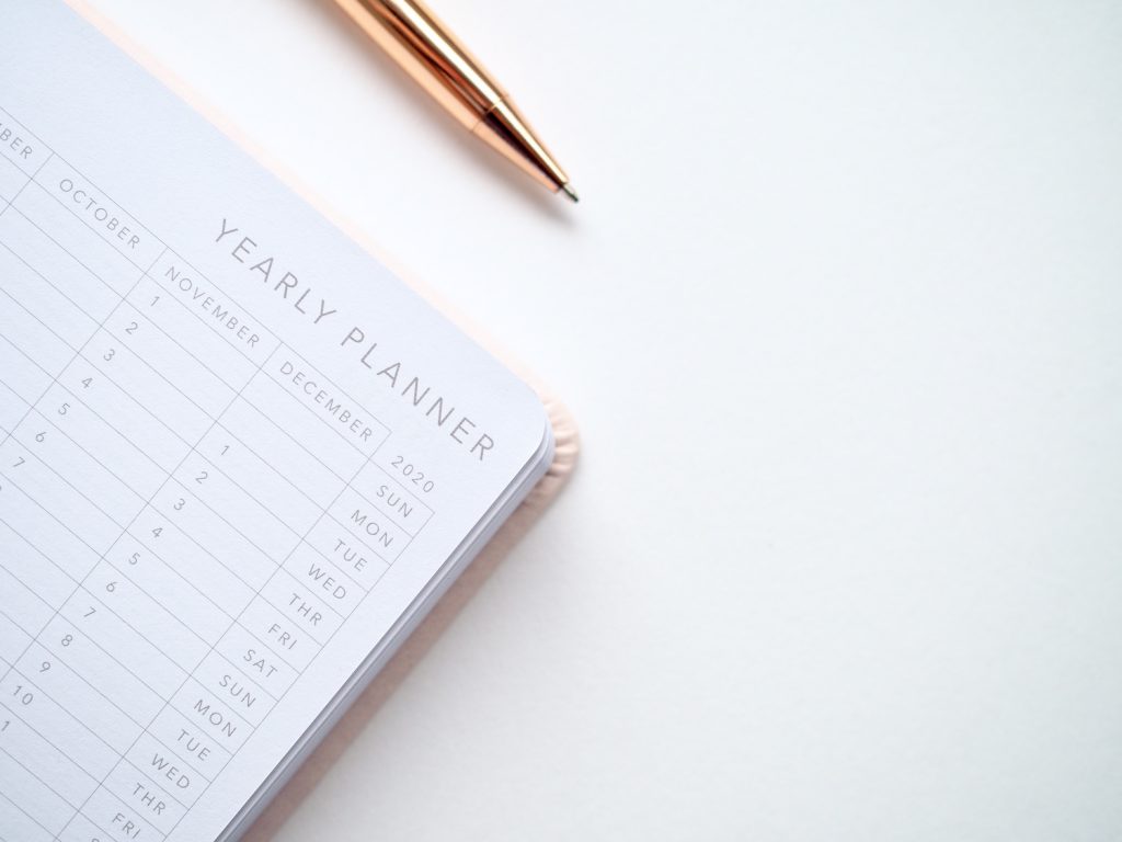 Close up photo of yearly planner beside a pen