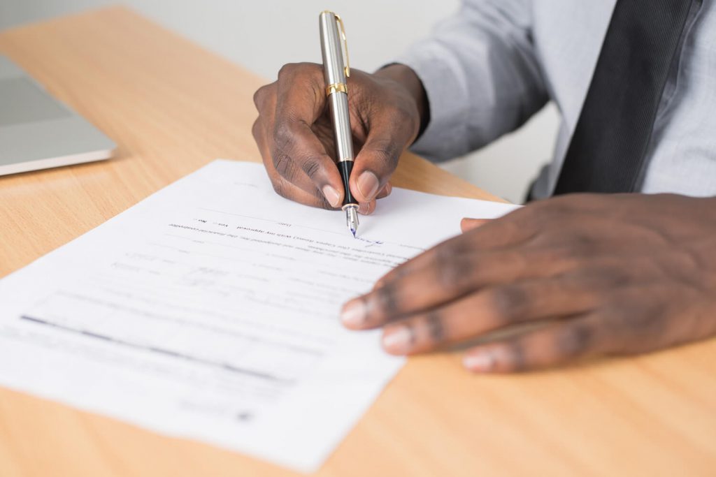 Person holding gray twist pen and white printer paper