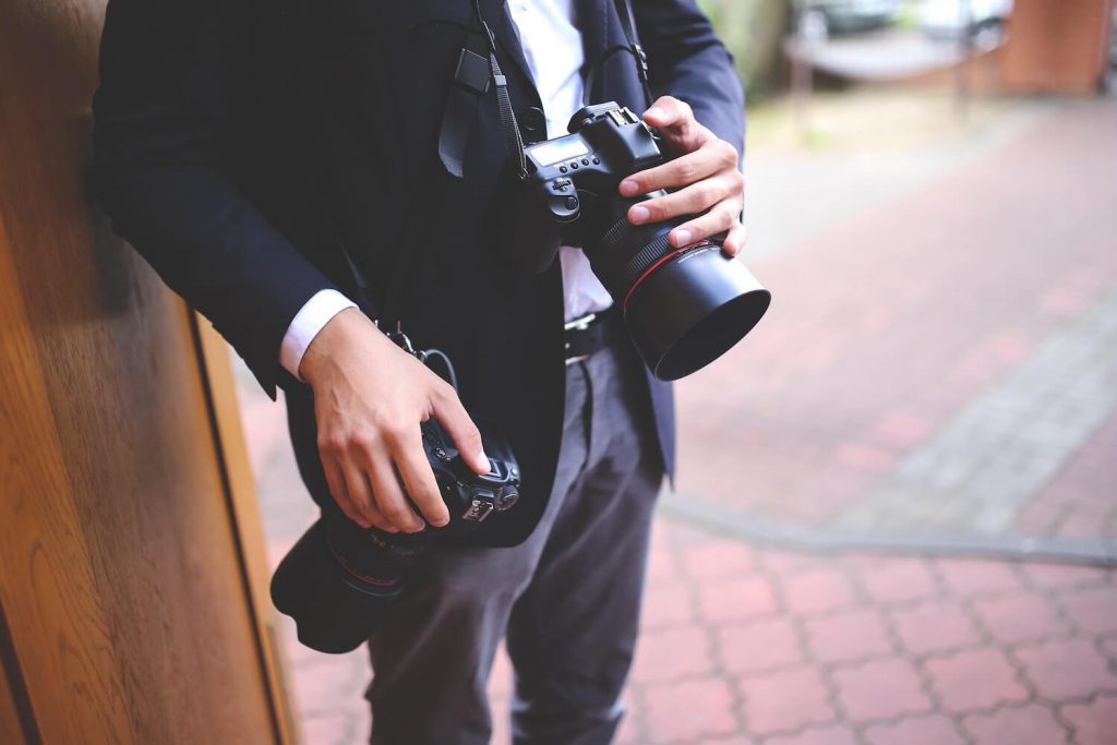 Person in suit holding two cameras
