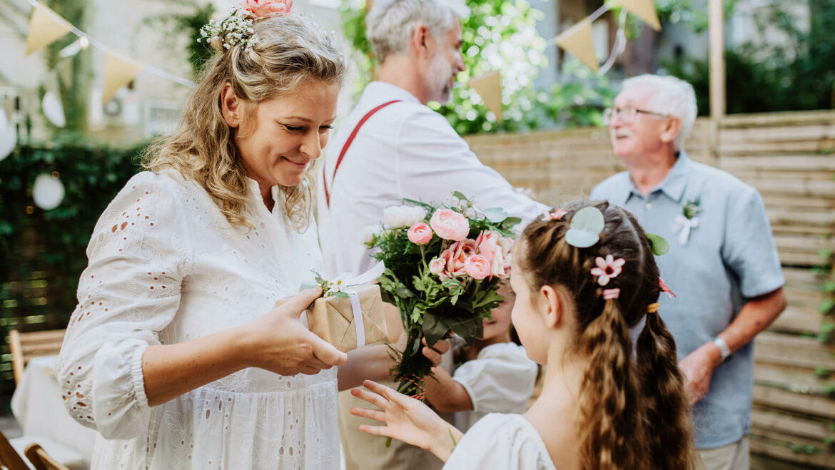 A bride receiving a gift from the flower girl in a wedding
