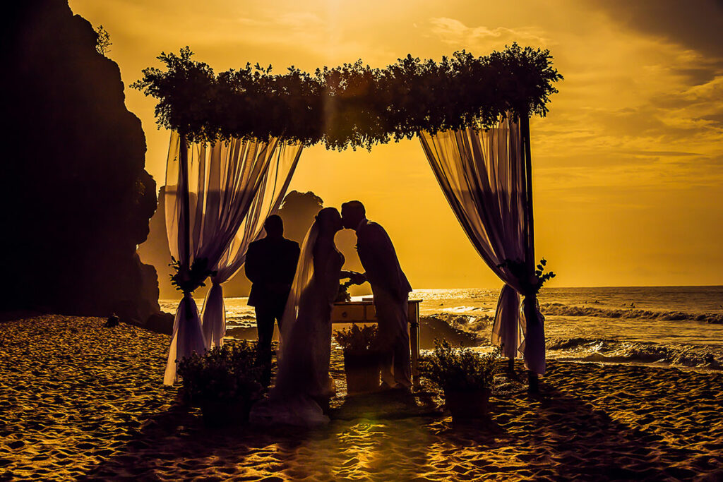 Couple getting married on the beach with golden hour wedding lighting