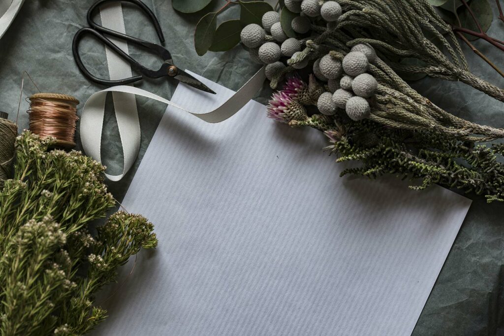 A DIY flower setup with dried flowers, greenery, scissors, chicken wire over a white paper
