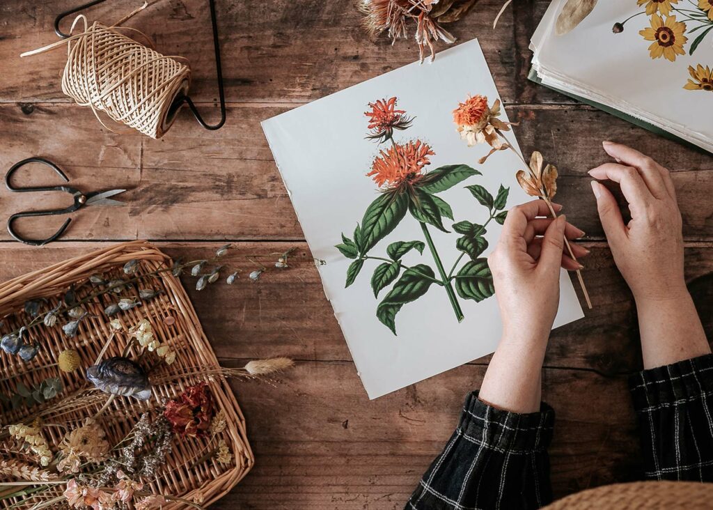 DIY flower table with hands arranging dried orange flowers with twine and scissors