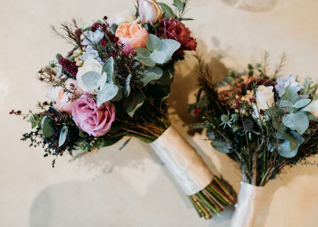 Wedding bouquet and smaller wedding party bouquet filled with greenery and flowers in a muted color palette