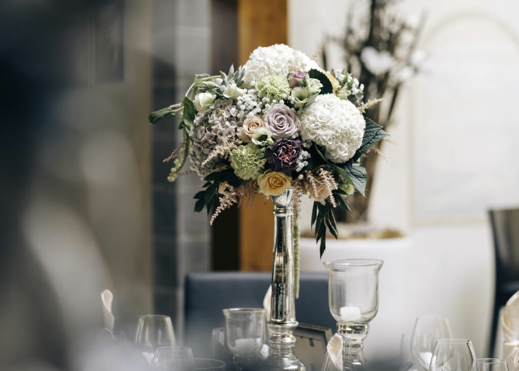 Tall wedding centerpiece with white, ivory, lavender and ivory flowers and greenery