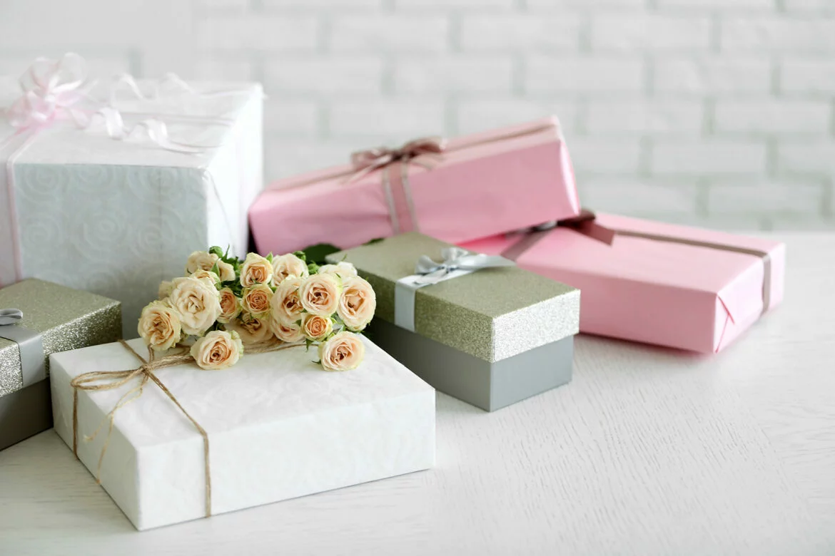 Several wrapped wedding shower gifts stacked on a table with flowers
