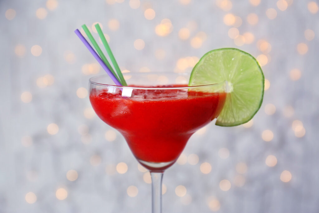 Strawberry daiquiri with two straws and a lime slice