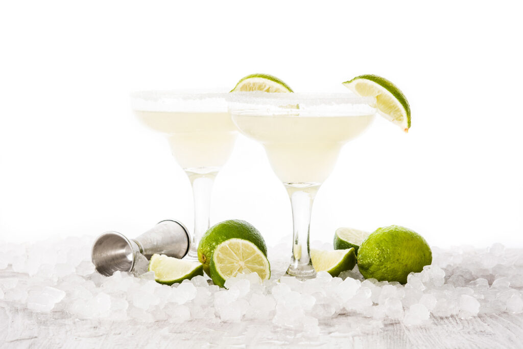 Two frozen margaritas with lime wedge garnish