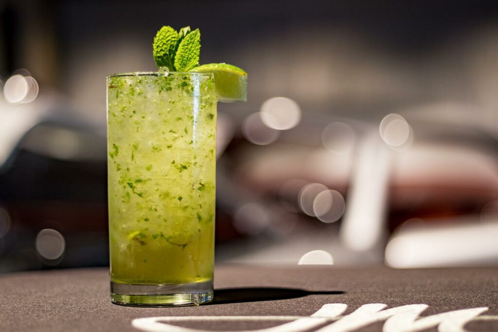 Mojito on a bartop with mint leaves and a lime wedge for garnish