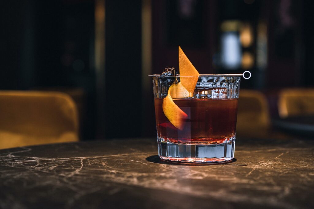 Old fashioned cocktail with orange peel and cocktail cherry 