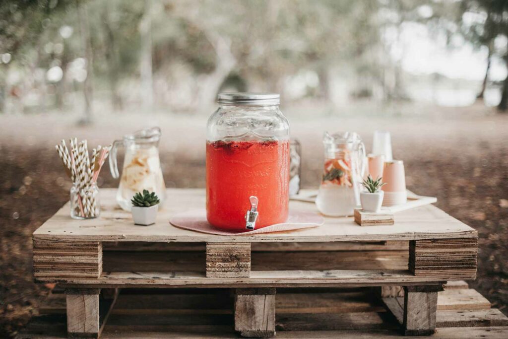 Dispenser of strawberry rosé punch and pitchers of water on drink table